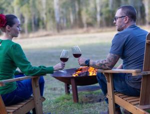 a man and woman sitting at a table with glasses of wine at Gumtop - Luxury Farmhouse Cabin in Bunburra