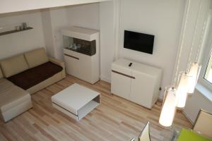 Elle comprend un petit salon doté d'un canapé et d'une télévision. dans l'établissement Apartament Light & Bright, à Międzyzdroje