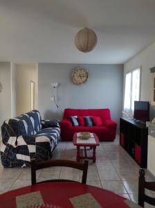 Una sala de estar con un sofá rojo y una mesa. en Location villa saisonniere a la campagne, en Saint-Théodorit