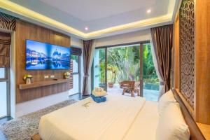 une chambre avec un grand lit avec une télévision au mur dans l'établissement New Primrose Pool Villa Your Own Secluded Paradise, à Ban Saiyuan (1)
