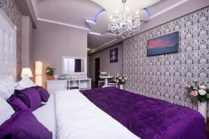 a bedroom with a large bed with purple sheets at Hotel De Paris in Krasnodar