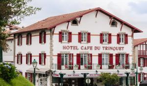 um hotel com persianas vermelhas num edifício em Hotel-Café du Trinquet em Cambo-les-Bains