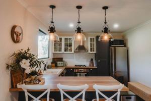 a kitchen with a wooden table and a refrigerator at Sugarloaf - Luxury Farmhouse Cabin in Bunburra