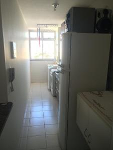 a kitchen with a white refrigerator and a window at Apartamento Guarapari com aconchego in Guarapari