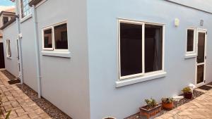 a white house with two windows and potted plants at Beachside Bliss in Tauranga +5 photos