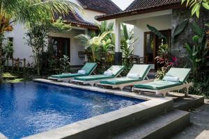 a pool with chaise lounge chairs next to a house at Sundhara View Ubud in Ubud