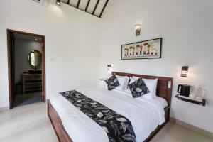 a bedroom with a large white bed with black and white pillows at Sundhara View Ubud in Ubud