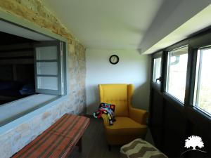 Sala de estar con silla amarilla y mesa en Albergue La Incera en San Martín