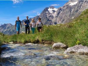 a group of people walking across a stream in the mountains at Alpine Bliss A Cosy Retreat in Antey-Saint-André