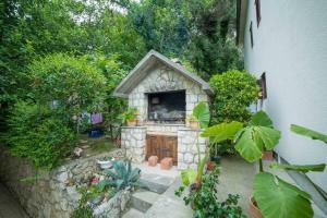 a small stone oven in a garden next to a building at Apartment Anica in Rab