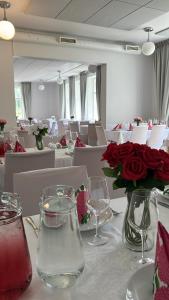 a table with a vase of roses and glasses on it at Kuopion Kesäranta in Kuopio
