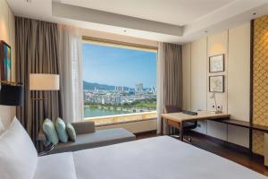 a hotel room with a bed and a desk and a window at Hilton Da Nang in Danang