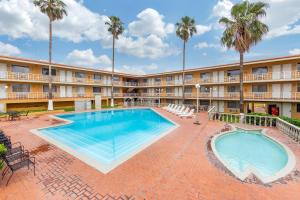 a pool in front of a hotel with palm trees at Quality Inn Piedras Negras in Piedras Negras