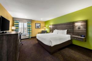 a hotel room with a bed and a flat screen tv at Quality Inn Warrensburg in Warrensburg