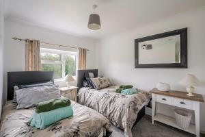 a bedroom with two beds and a mirror on the wall at Rosabelle in Wivenhoe