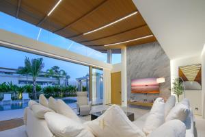 a living room with white couches and a tv at Asherah Villa By Asherah Team in Ban Phru Champa