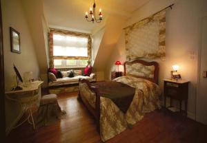 1 dormitorio con cama, sofá y ventana en Chambre d'hôtes du Moulin de Landonvillers, en Courcelles-Chaussy