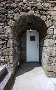 a stone wall with a white door in a stone building at Casa do Simão in Nordeste
