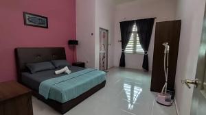 a bedroom with a bed and a pink wall at Adyan Homestay Terengganu in Bukit Payong