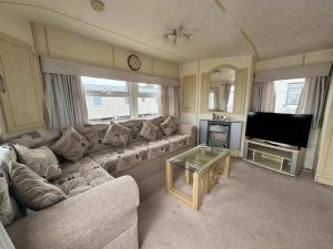 a living room with a couch and a television at TM61 3 bed CARAVAN oN THE GOLDEN PALM PET friendly in Chapel Saint Leonards