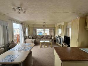 a living room with a couch and a table at TM61 3 bed CARAVAN oN THE GOLDEN PALM PET friendly in Chapel Saint Leonards