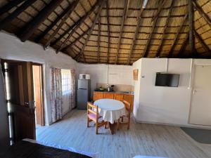 a kitchen with a table and a white refrigerator at Pavlovna Comfy 4 Cottage in Himeville