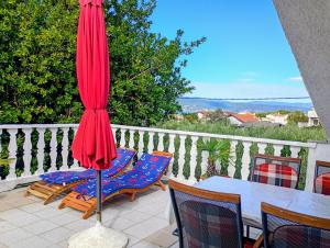 a patio with a red umbrella and a table and chairs at Apartment Marina in Brzac