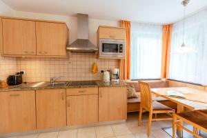 a kitchen with wooden cabinets and a table with a dining room at Haus Angelika in Nova Levante +21 photos