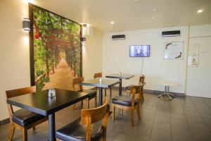 a restaurant with tables and chairs and a wall mural at Abbots Hamilton – Hotel and Conference Centre in Hamilton