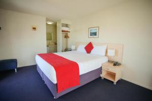 a bedroom with a large bed with a red blanket at Abbots Hamilton – Hotel and Conference Centre in Hamilton