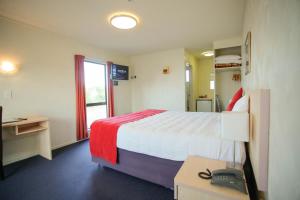 a hotel room with a bed and a desk with a telephone at Abbots Hamilton – Hotel and Conference Centre in Hamilton
