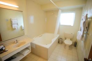 a bathroom with a tub and a sink and a toilet at Abbots Hamilton – Hotel and Conference Centre in Hamilton