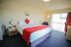 a bedroom with a large bed with a red blanket at Abbots Hamilton – Hotel and Conference Centre in Hamilton