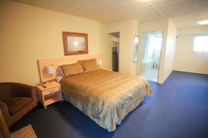 a hotel room with a bed and a chair at Abbots Hamilton – Hotel and Conference Centre in Hamilton