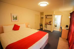 a bedroom with a bed with a red and white blanket at Abbots Hamilton – Hotel and Conference Centre in Hamilton