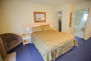 a hotel room with a bed and a chair at Abbots Hamilton – Hotel and Conference Centre in Hamilton