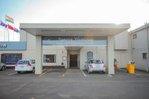 two cars parked in a parking lot in front of a building at Abbots Hamilton – Hotel and Conference Centre in Hamilton