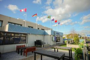 a group of flags flying above a building with benches at Abbots Hamilton – Hotel and Conference Centre in Hamilton