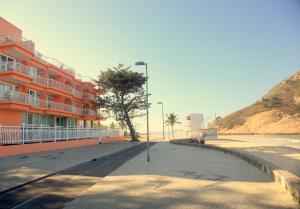 a street in front of a building with a tree at KS Beach Hotel in Rio de Janeiro