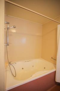 a bath tub in a bathroom with a shower at Abbots Hamilton – Hotel and Conference Centre in Hamilton