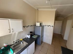 a small kitchen with a sink and a refrigerator at Pavlovna Bunk with the kids Cottage in Himeville +2 photos