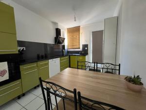 a large kitchen with a wooden table and chairs at Bel appartement T2 avec jardin indépendant in Pérols