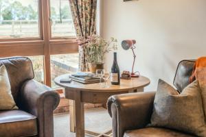 a living room with two chairs and a table and a window at Poplar Cottage - Historic Barn in Dumbleton in Dumbleton