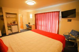 a bedroom with a bed and a window and a desk at Abbots Hamilton – Hotel and Conference Centre in Hamilton
