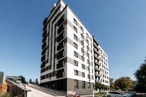 a tall white and black building with a parking lot at Matcha Studio in Bucharest
