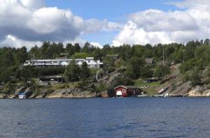 a small red house on the shore of a lake at Sjøverstø Holiday in Tvedestrand