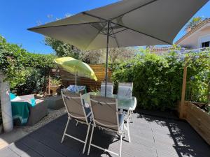 a table and chairs with an umbrella on a patio at Bel appartement T2 avec jardin indépendant in Pérols
