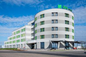 a white building with a green sign on top at ibis Styles Debrecen Airport in Debrecen