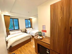 a bedroom with two beds and a desk in it at Hotel Thanh Phương 1 in Mèo Vạc