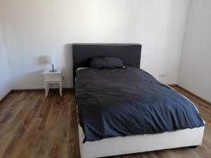 a bed in a white bedroom with a wooden floor at Allgäu Space in Marktoberdorf